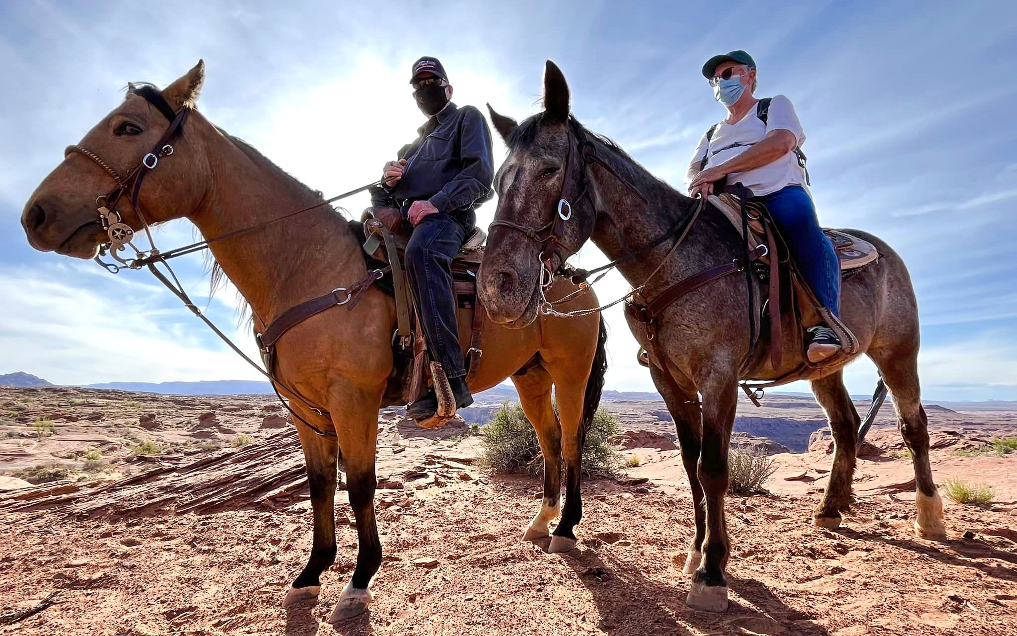 Horseback riders on a trail at Horseshoe Bend with desert landscape in the background.