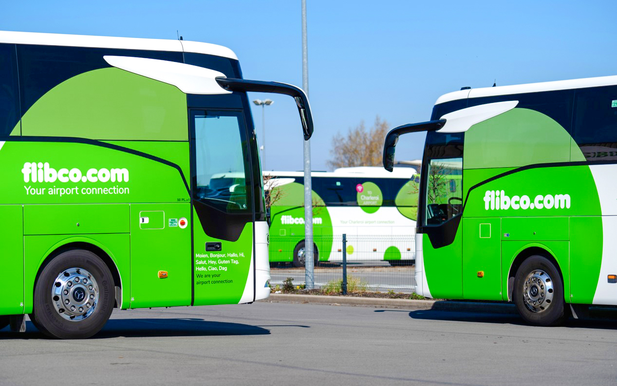 Green airport shuttle buses parked in a lot, flibco.com branding visible.