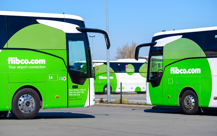Green airport shuttle buses parked in a lot, flibco.com branding visible.
