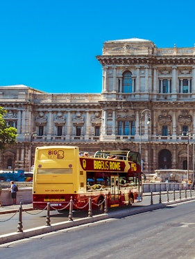 Big Bus Rome tour passing by historic building in Rome, Italy.