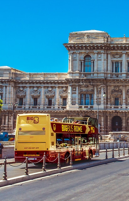 Big Bus Rome tour passing by historic building in Rome, Italy.