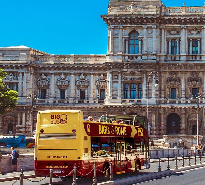 Open-top double-decker bus touring past the Colosseum in Rome, Italy.
