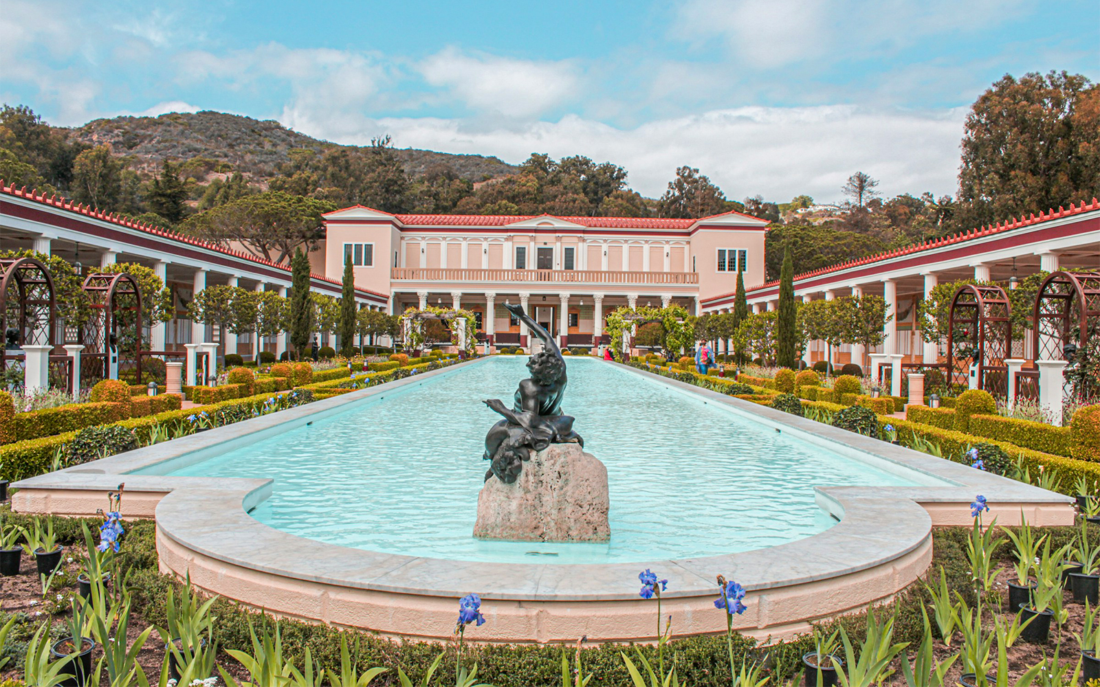 Villa of the Papyri courtyard with central pool and statue, surrounded by gardens and columns.