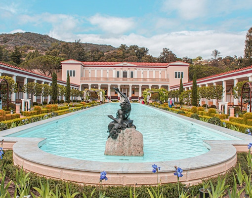 Villa of the Papyri courtyard with central pool and statue, surrounded by gardens and columns.