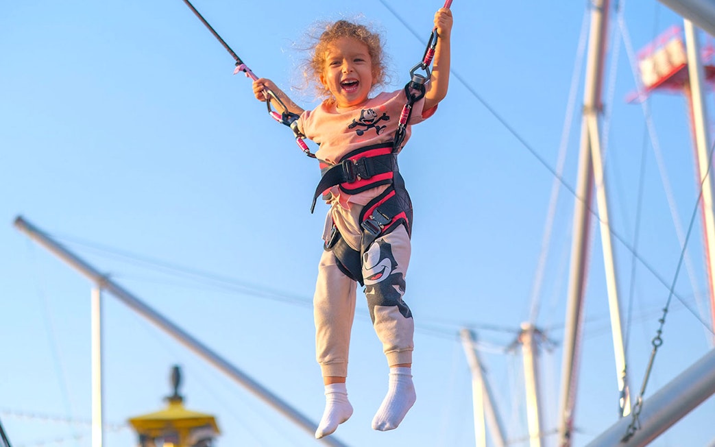 Child enjoying bungee trampoline at Global Village carnival.