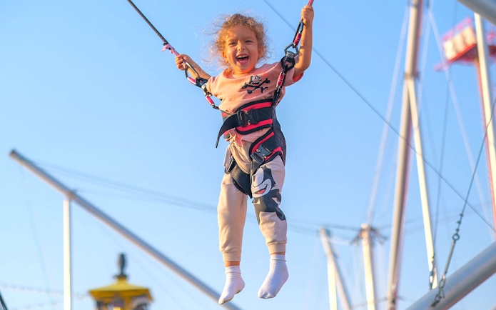 Child enjoying bungee trampoline at Global Village carnival.