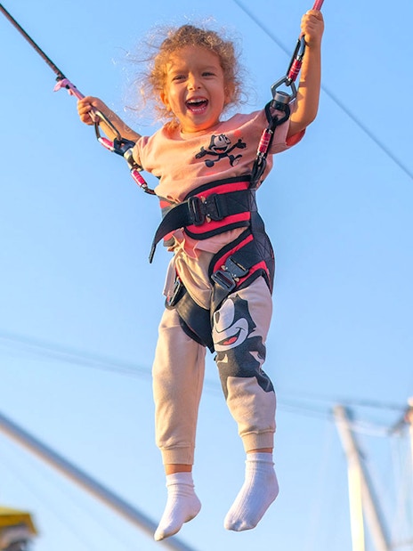 Child enjoying bungee trampoline at Global Village carnival.