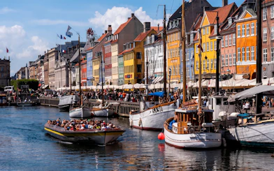 Sightseeing boat on Nyhavn Canal in Copenhagen with colorful buildings.