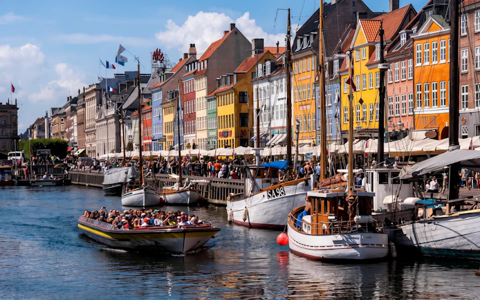 Sightseeing boat on Nyhavn Canal in Copenhagen with colorful buildings.