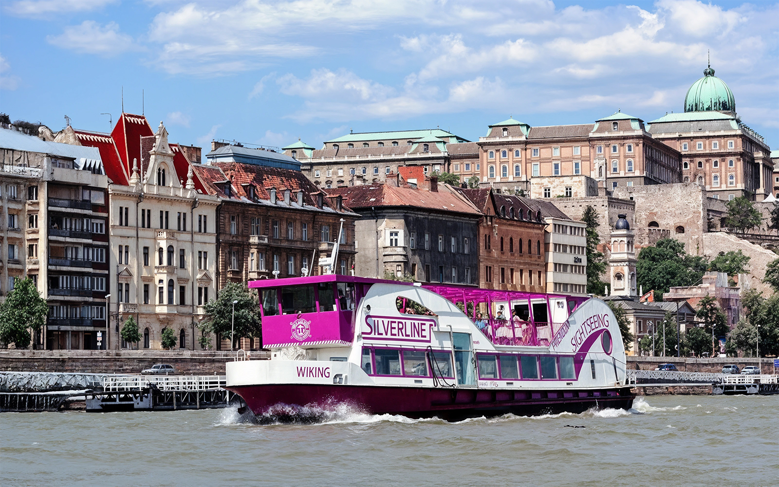 Cruise boat on the Danube River with Budapest architecture in the background.