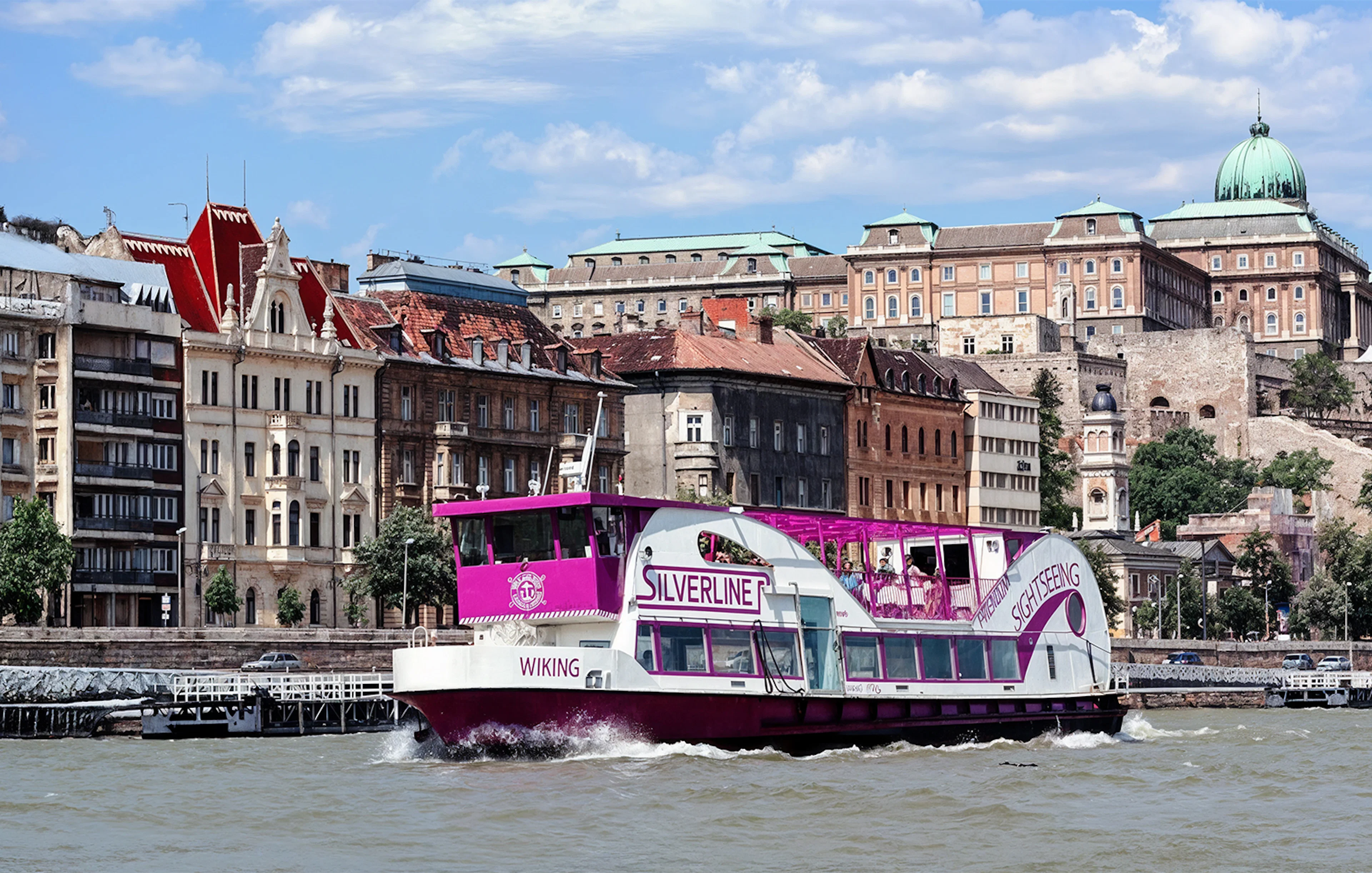 Cruise boat on the Danube River with Budapest architecture in the background.