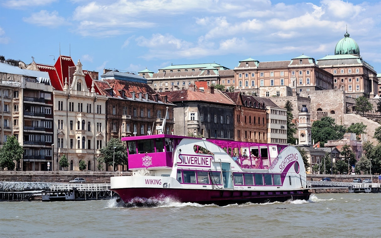 Cruise boat on the Danube River with Budapest architecture in the background.