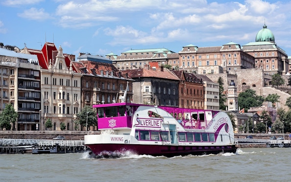 Cruise boat on the Danube River with Budapest architecture in the background.