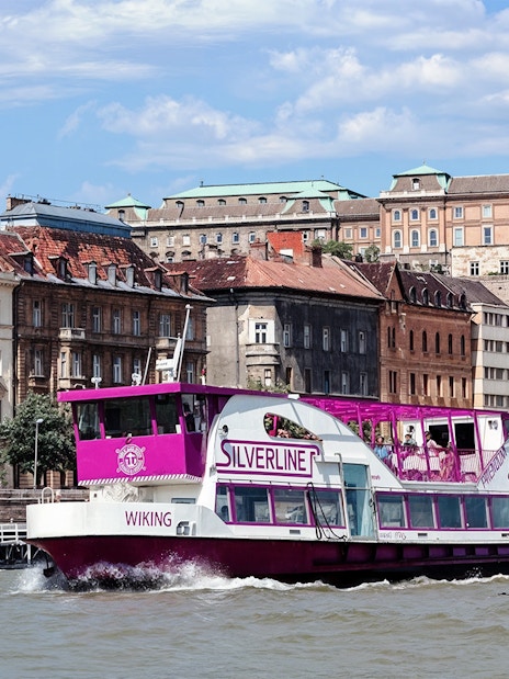 Cruise boat on the Danube River with Budapest architecture in the background.