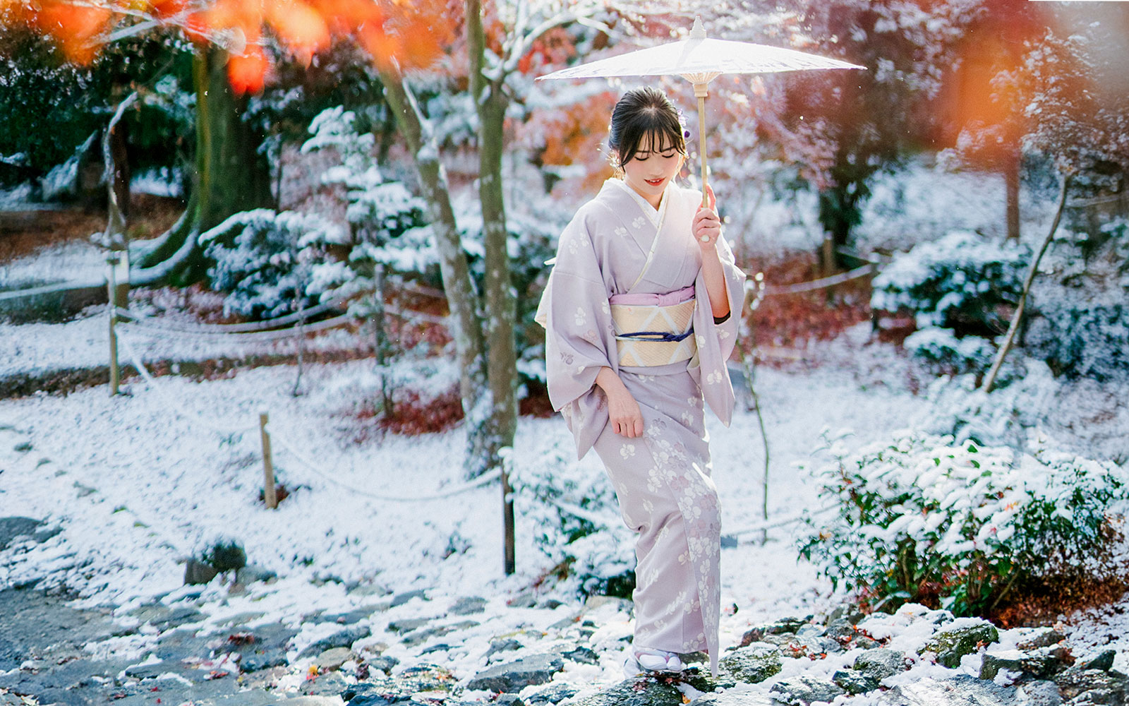 Woman in kimono with umbrella in snowy Arashiyama, Kyoto.