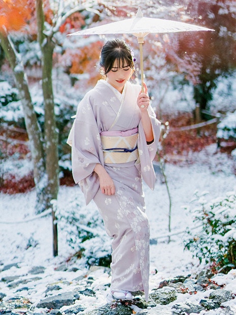 Woman in kimono with umbrella in snowy Arashiyama, Kyoto.