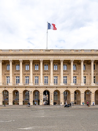 Hôtel de la Marine facade with French flag in Paris, France.