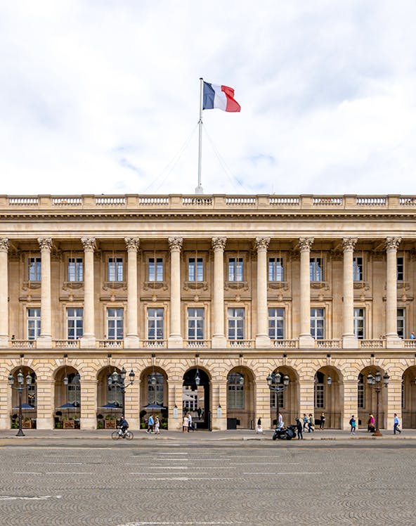 Hôtel de la Marine facade with French flag in Paris, France.