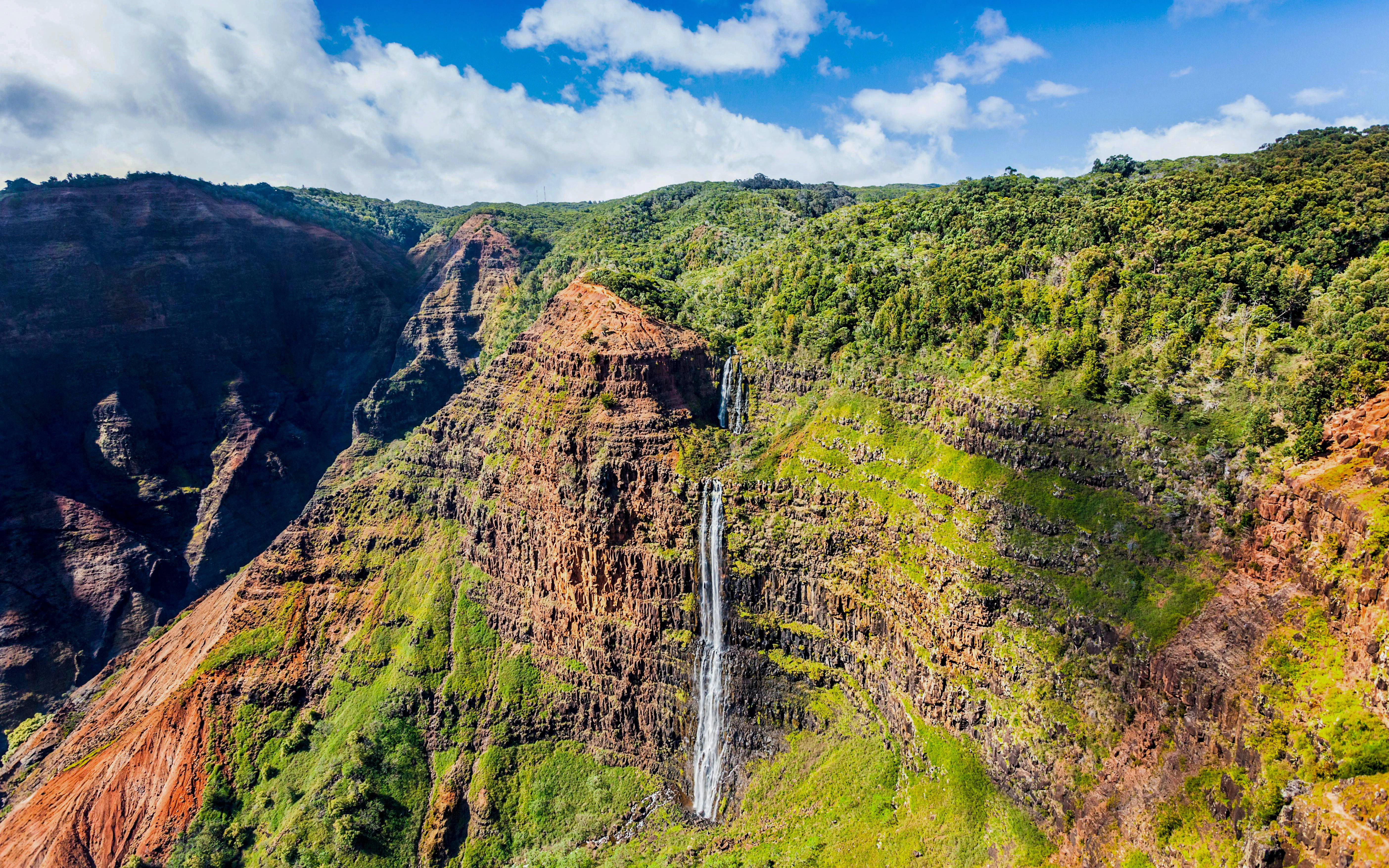 Manawaiopuna Falls cascading down lush cliffs in Kauai, Hawaii.