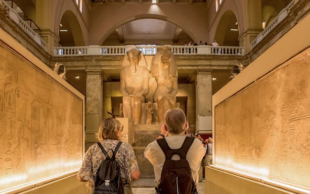 Visitors exploring statues and hieroglyphs at the Egyptian Museum in Cairo.