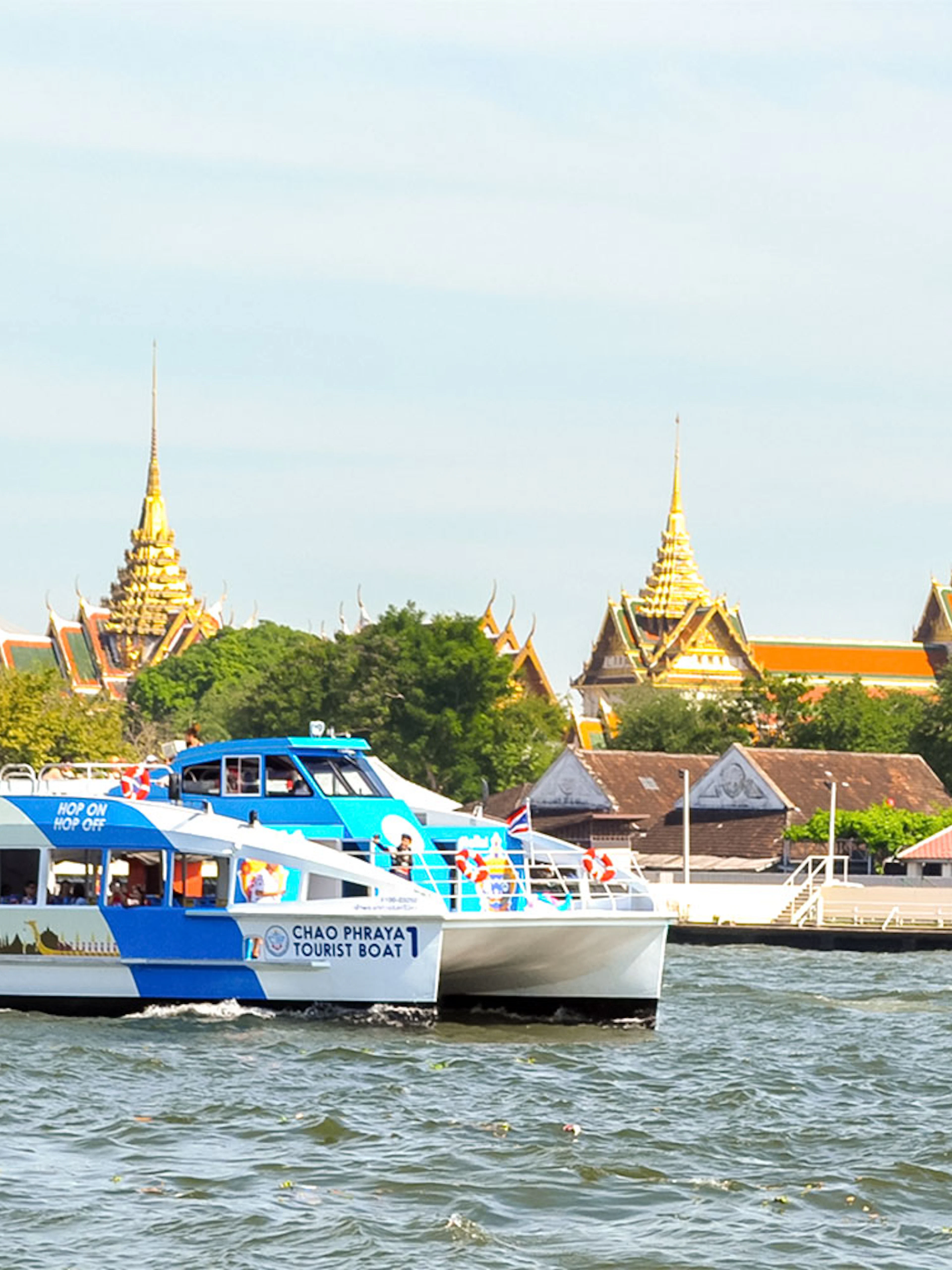 Tourists on Chao Phraya boat with Bangkok temples in the background.