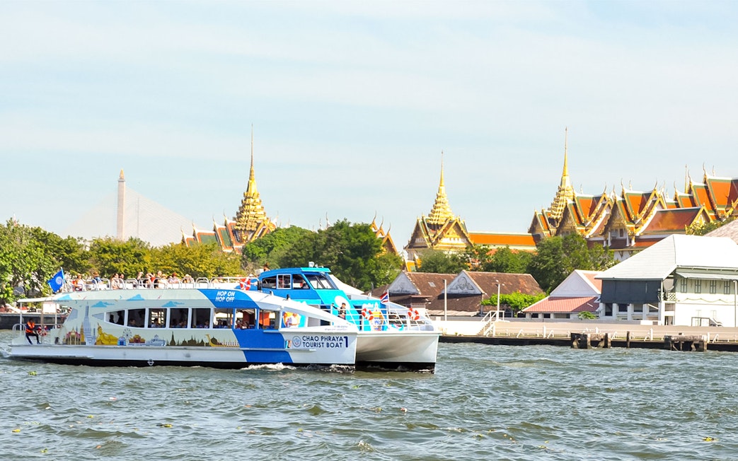 Tourists on Chao Phraya boat with Bangkok temples in the background.