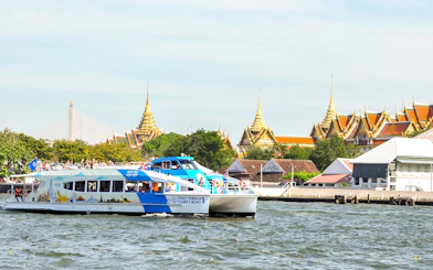 Tourists on Chao Phraya boat with Bangkok temples in the background.