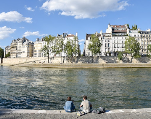Île Saint-Louis Paris, view of historic buildings along the Seine River with a bridge in the background.