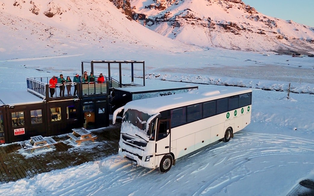 Bus for glacier expedition transfers at Vatnajökull with snowy mountain backdrop.