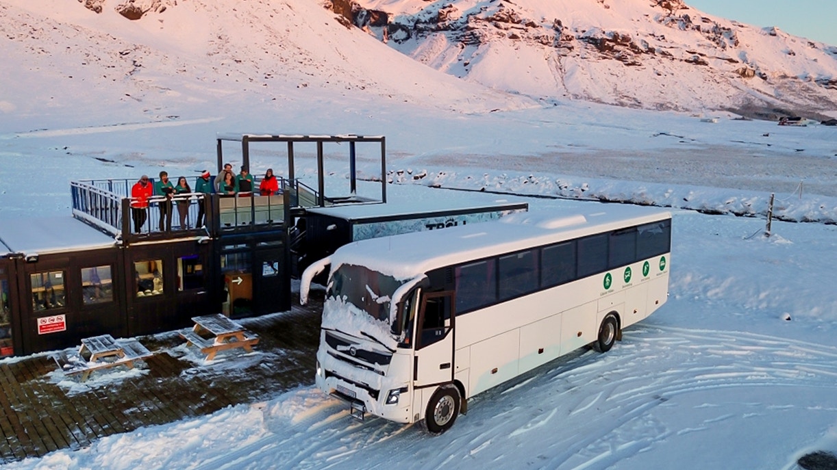 Bus for glacier expedition transfers at Vatnajökull with snowy mountain backdrop.
