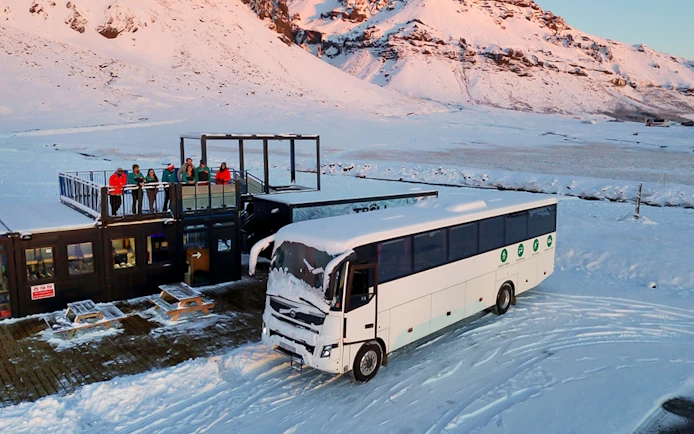 Bus for glacier expedition transfers at Vatnajökull with snowy mountain backdrop.