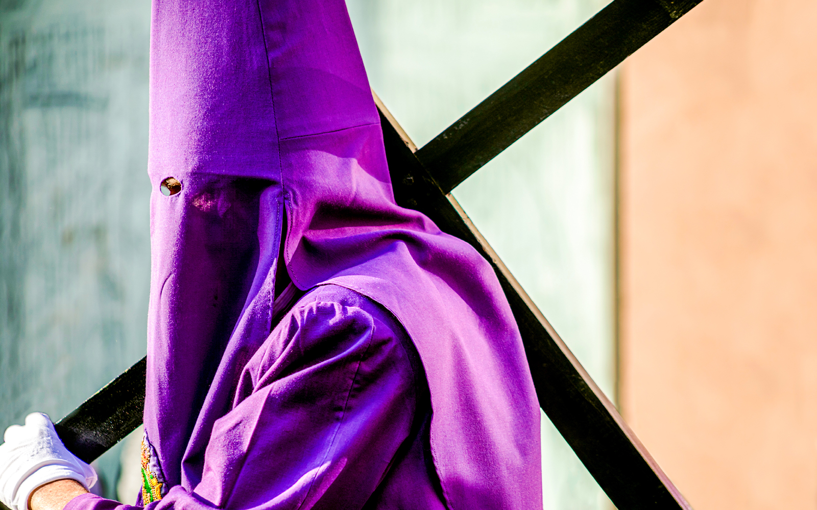 Nazareno carrying a cross in a hooded robe during Good Friday procession, Paris.