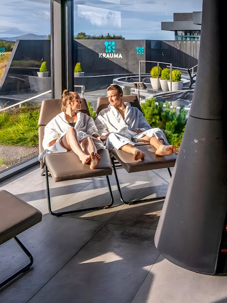 Couple relaxing in robes by a fireplace at Krauma Geothermal Baths, Iceland.