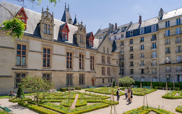 Courtyard garden at Hôtel de Sens in the Marais, Paris, with visitors exploring.