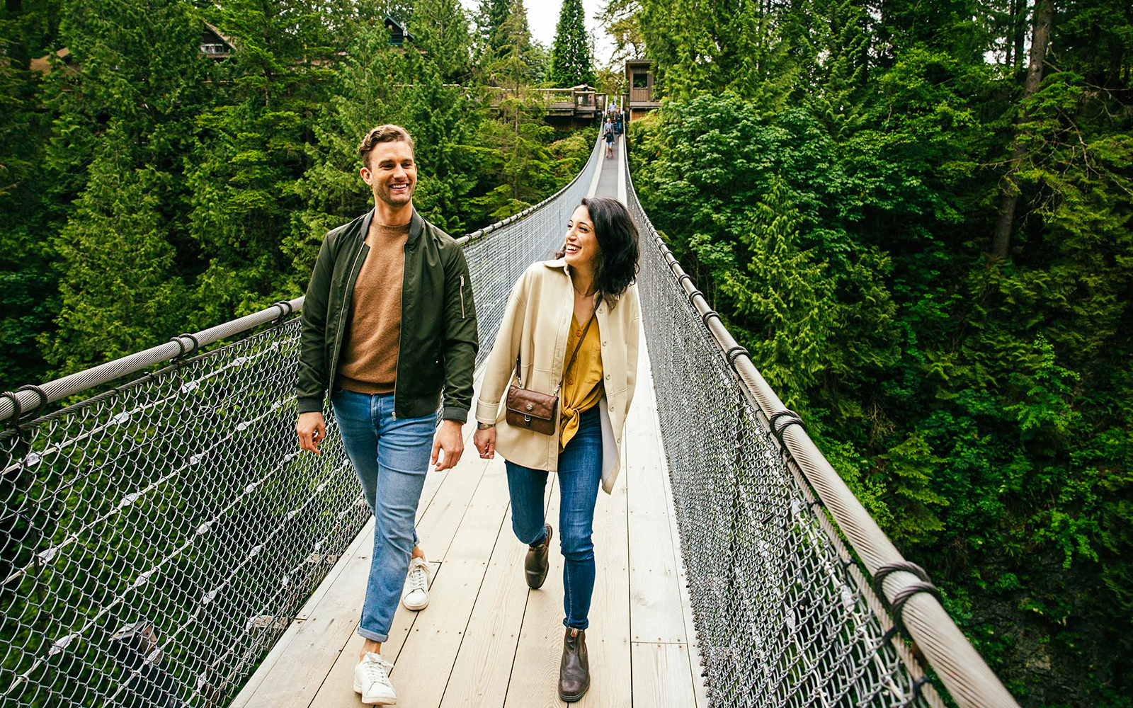 Visitors walking on Capilano Suspension Bridge surrounded by lush forest.
