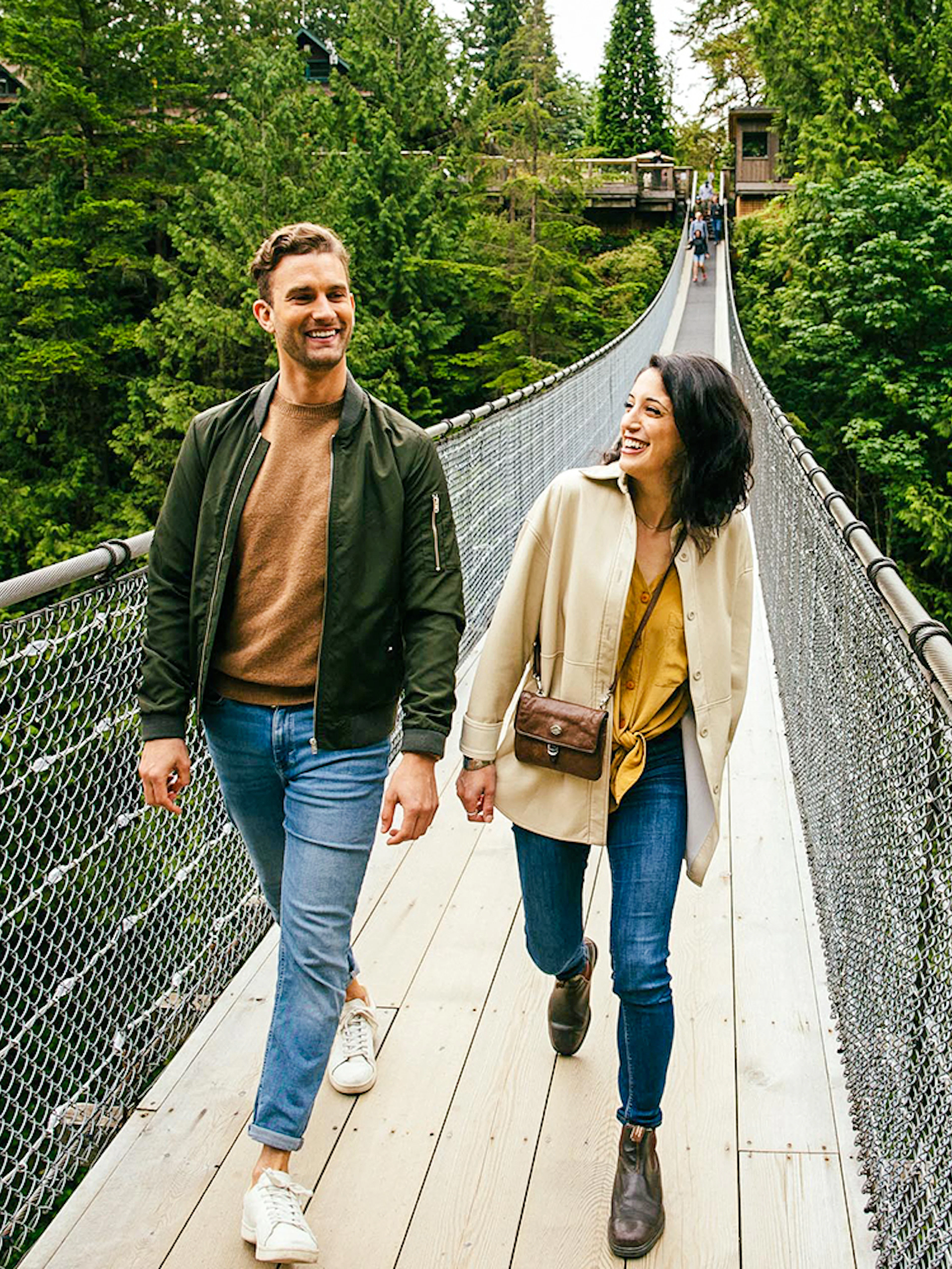 Visitors walking on Capilano Suspension Bridge surrounded by lush forest.
