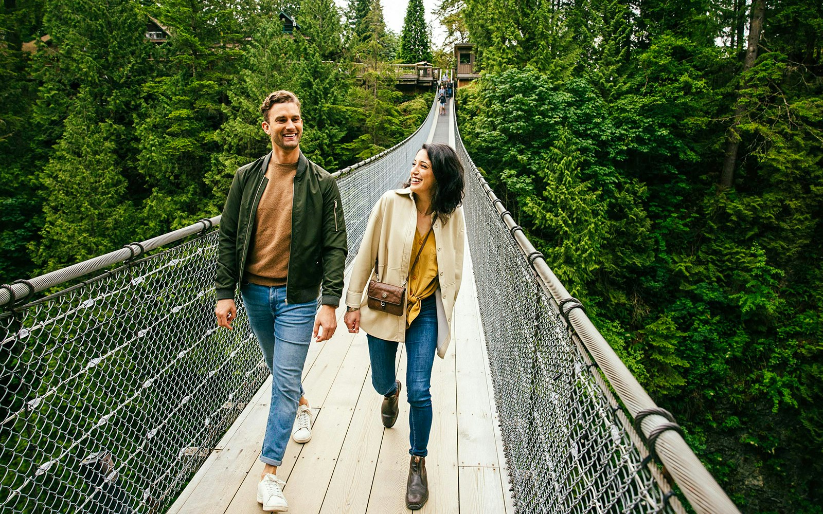 Visitors walking on Capilano Suspension Bridge surrounded by lush forest.