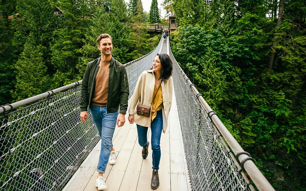 Visitors walking on Capilano Suspension Bridge surrounded by lush forest.