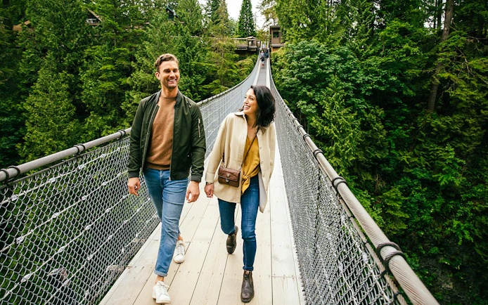 Visitors walking on Capilano Suspension Bridge surrounded by lush forest.