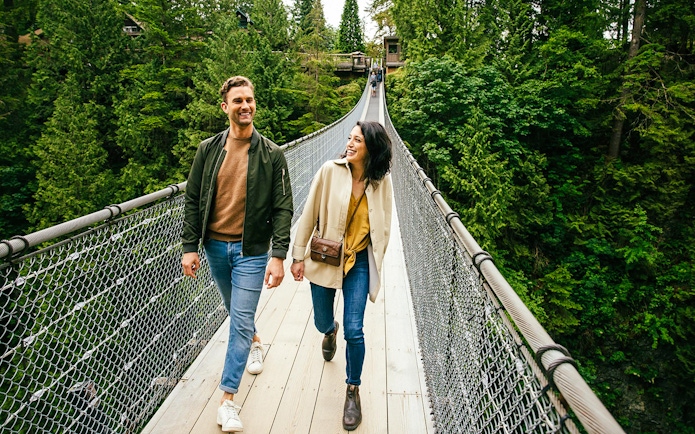 Visitors walking on Capilano Suspension Bridge surrounded by lush forest.