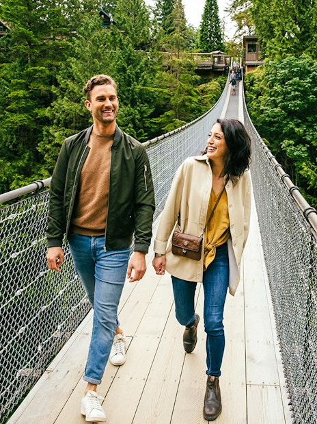 Visitors walking on Capilano Suspension Bridge surrounded by lush forest.
