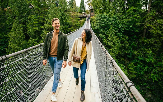 Visitors walking on Capilano Suspension Bridge surrounded by lush forest.
