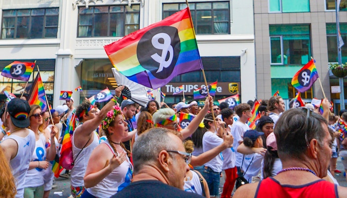 Participants celebrating at the Pride parade in New York City, June, with colorful flags and vibrant outfits.