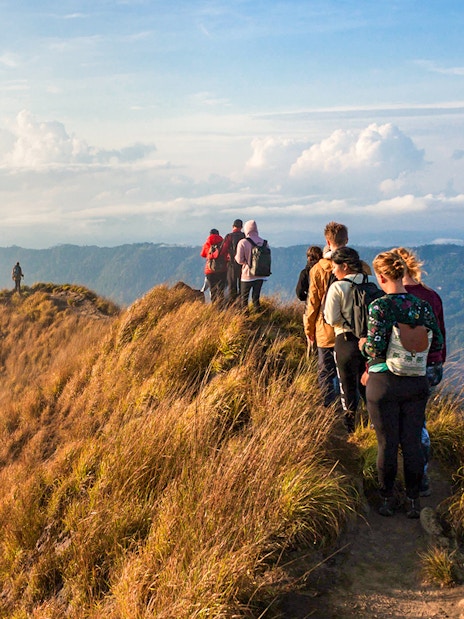 Group trekking along Mount Batur ridge at sunrise, Bali.