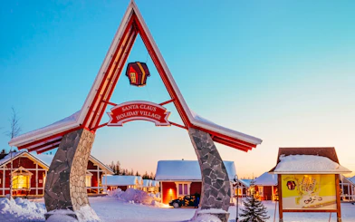 Santa Claus Village entrance with snow-covered cabins in Rovaniemi.