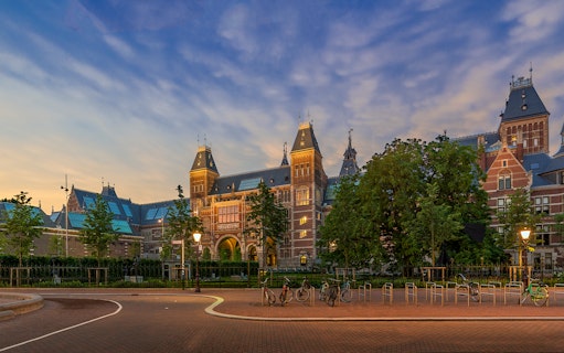 Rijksmuseum exterior with bicycles in Amsterdam at sunset.