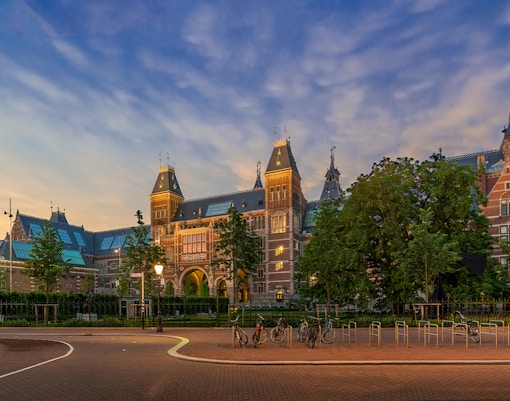 Rijksmuseum exterior with bicycles in Amsterdam at sunset.