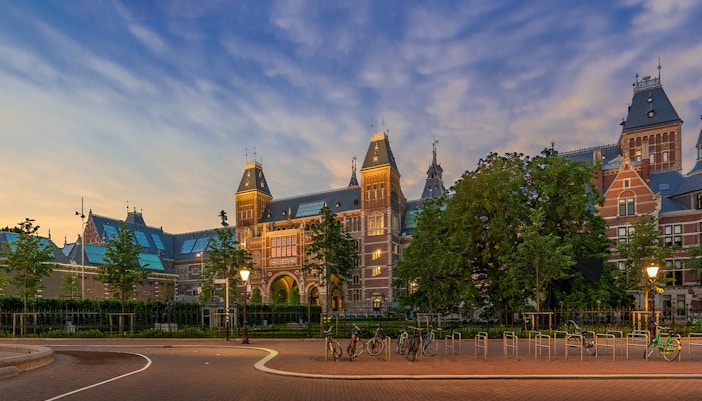 Rijksmuseum exterior with bicycles in Amsterdam at sunset.