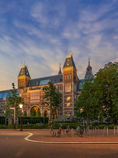 Rijksmuseum exterior with bicycles in Amsterdam at sunset.