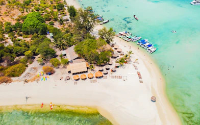 Aerial view of Koh Samui Pig Island with beach huts, boats, and turquoise water.
